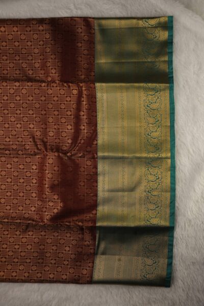 Close-up texture of the maroon blended silk body showing the classic gold zari checks (kattam) alongside the heavy, intricate gold zari work of the sea green Kanchi border.