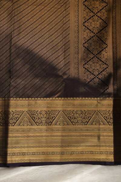 A detailed full view of the rich, dense gold zari geometric diamond brocade pallu woven on the magenta base of the semi pattu silk saree.