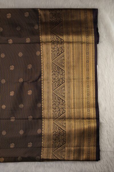 Close-up texture of the dark chocolate blended silk body showing the vintage gold zari lines alongside the heavy, intricate gold zari work of the magenta Kanchi border.
