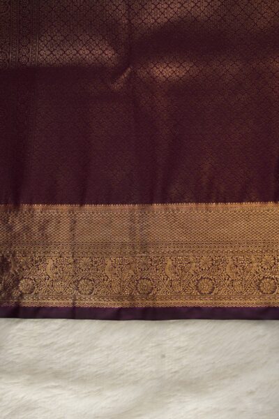 A detailed full view of the rich, dense gold zari geometric diamond brocade pallu woven on the dark wine base of the semi pattu silk saree.