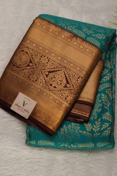 Elegantly folded outlook of the green semi pattu art silk saree, displaying the stunning contrast between the vibrant green body with leaf buttis and the rich coffee brown border.