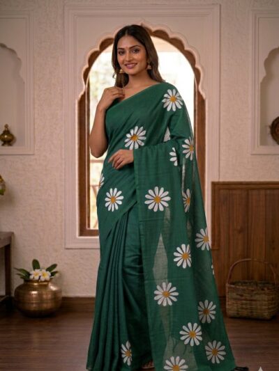 Smiling woman wearing a rich dark green khadi cotton saree with scattered white daisy floral prints and a matching pallu with black tassels.