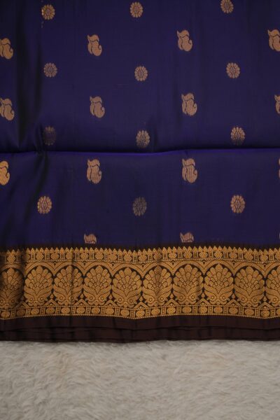Close-up texture of a navy blue lightweight Kanchi silk saree with alternating floral and paisley metallic buttis, alongside a beautifully detailed snuff brown gold zari border.