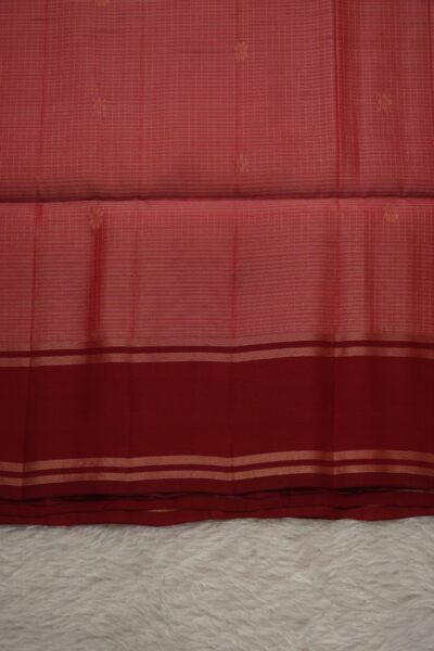 Close-up texture of a peach lightweight Pattu saree with woven checks and floral buttis, alongside a sleek deep red gap border with zari lines.