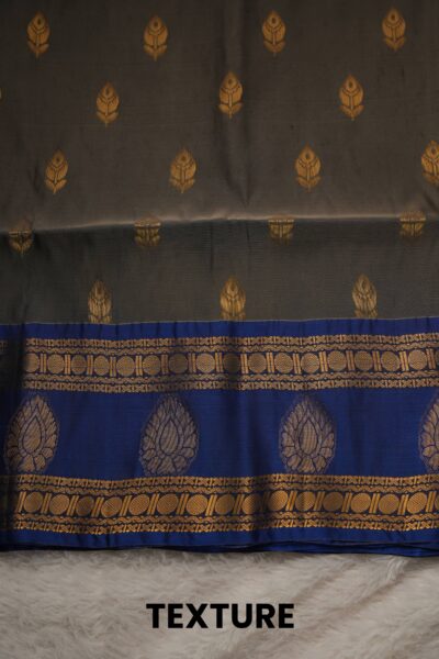Close-up texture of a dark olive green lightweight Pattu saree with gold leaf buttis, alongside a beautifully detailed royal blue gold zari border featuring chakram patterns.