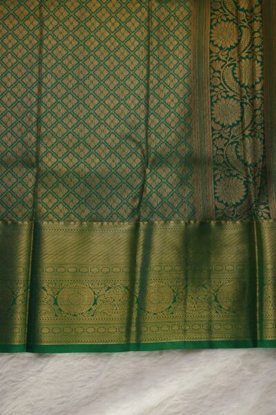 A detailed full view of the rich, dense gold zari geometric diamond brocade pallu woven on the vibrant green base of the semi pattu silk saree.