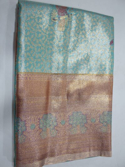 Folded Aqua Green Semi Kanchi Pattu saree showcasing all-over gold zari floral brocade, a Meenakari peacock motif, and a heavy metallic mauve-copper border with green floral tree meenakari patterns.