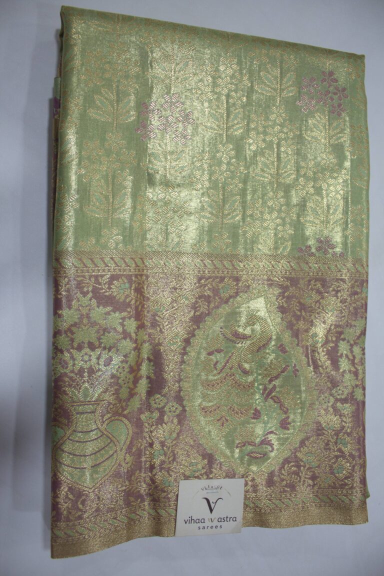 Folded Pista Green Semi Kanchi Pattu saree showing an all-over gold zari botanical brocade and a heavy metallic mauve border with a large peacock paisley and floral vase motif accented with Meenakari weaving.
