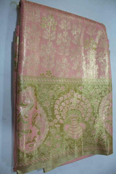 Folded Pink Semi Kanchi Pattu saree showing an all-over gold zari botanical brocade and a heavy metallic olive-gold border with a large peacock paisley and floral vase motif accented with pink Meenakari weaving.
