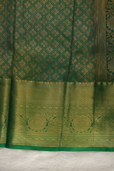 A detailed full view of the rich, dense gold zari geometric diamond brocade pallu woven on the vibrant green base of the semi pattu silk saree.