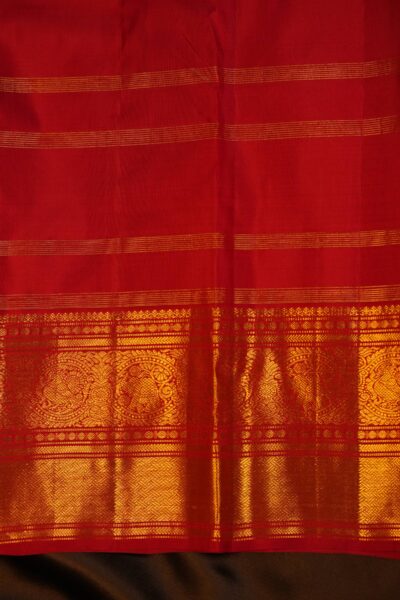 Matching red unstitched blouse piece with delicate zari stripes and an intricate Kanchi gold border for the handloom Kanjeevaram saree.
