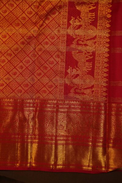A detailed half-view of the majestic gold zari pallu and traditional Kanchi border on the red pure handloom Kanjeevaram saree.