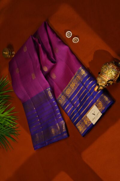 Top view of the folded pink pure handloom Kanjeevaram Pattu saree showcasing the stunning blue vintage gap border and scattered gold buttis.