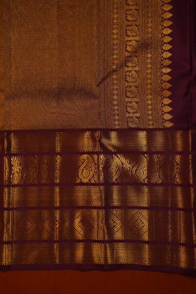 Close-up highlighting the intricate transition between the geometric diamond brocade pallu and the traditional peacock motifs on the heavy maroon border.