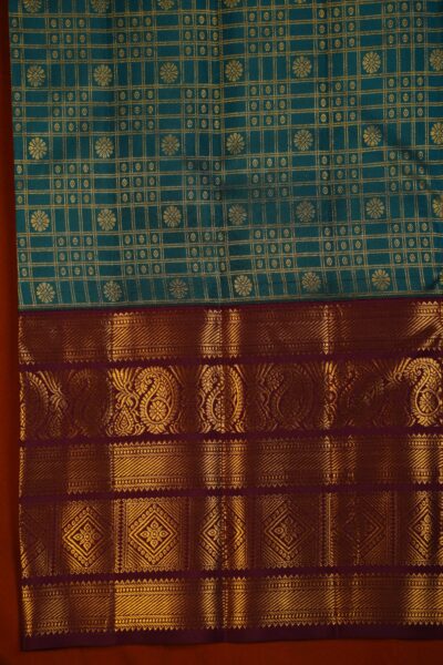 Close-up texture of the pure handloom tea green silk body showing woven gold checks and buttis alongside the heavy, intricate gold zari work of the maroon Kanchi border.