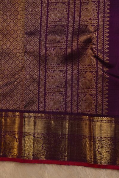 Close-up highlighting the intricate transition between the geometric diamond brocade pallu and the traditional peacock motifs on the magenta border.