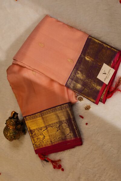 Beautifully draped outlook of the pure handloom Kanjeevaram pattu saree, displaying the stunning contrast between the peach silk and the magenta vintage gap border.