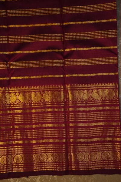 Matching maroon unstitched blouse piece featuring the vintage gold zari lines and the intricate Kanchi border, perfectly complementing the handloom saree.