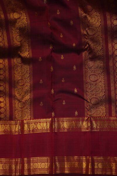 Close-up highlighting the intricate transition between the geometric diamond brocade pallu and the traditional peacock motifs on the heavy maroon border.