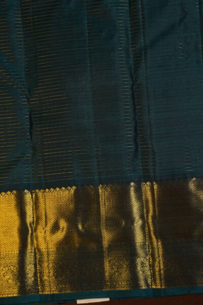 Contrast navy blue unstitched blouse piece featuring vintage gold zari lines and the intricate Kanchi border, perfectly matching the warm peach handloom saree.