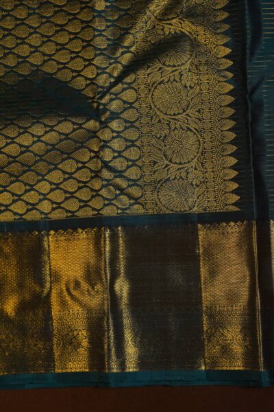 Close-up highlighting the intricate transition between the geometric diamond brocade pallu and the traditional peacock motifs on the heavy navy blue border.