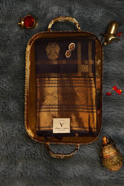Top view of the beautifully folded self brown pure handloom Kanjeevaram Pattu saree resting on a decorative brass tray, showcasing the delicate gold checks and heavy border.