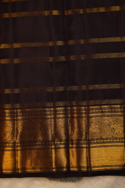 Matching dark brown unstitched blouse piece featuring fine gold zari lines and the intricate Kanchi border, perfectly complementing the handloom checked saree.