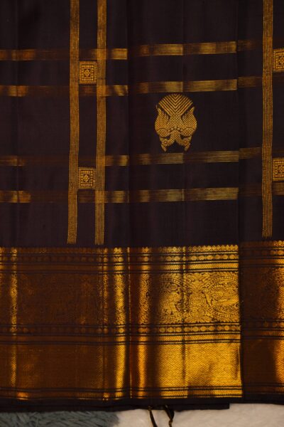 Close-up texture of the pure handloom brown silk body showing the woven vintage gold zari checks, alongside the heavy, intricate gold work of the Kanchi border.