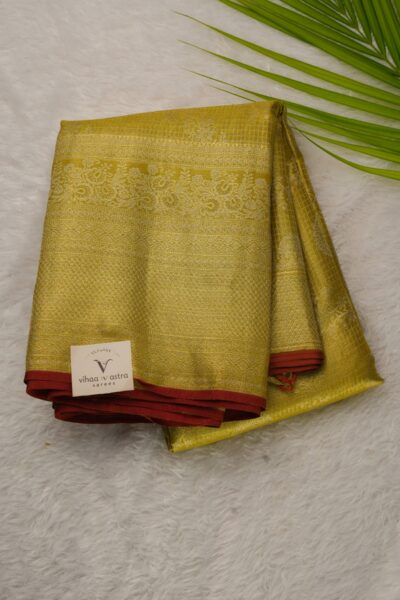 Folded golden yellow pure tissue Kanjeevaram Pattu saree showcasing fine zari checks, floral motifs, and an intricately woven border with red piping.