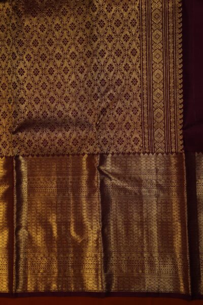 Close-up highlighting the intricate transition between the geometric diamond brocade pallu and the traditional peacock motifs on the maroon border.