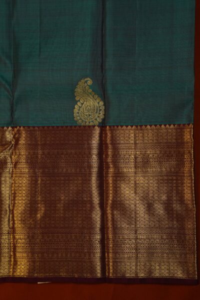 Close-up texture of the pure handloom tea green silk body showing woven gold buttis alongside the heavy, intricate gold zari work of the maroon Kanchi border.