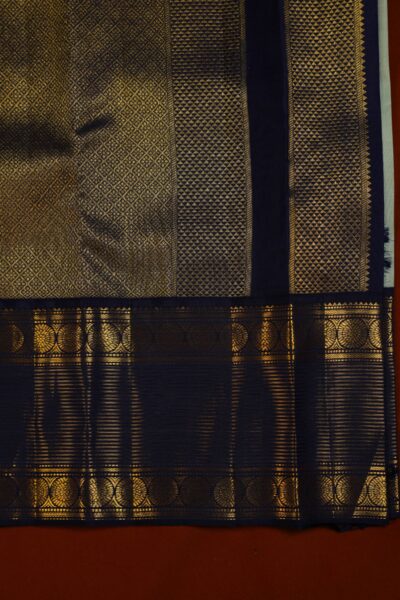 Close-up highlighting the intricate transition between the geometric diamond brocade pallu and the traditional peacock motifs on the heavy navy blue border.