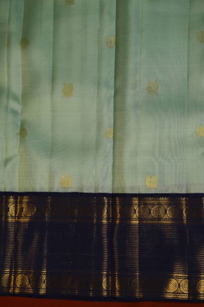 Close-up texture of the pure handloom pista green silk body showing woven vintage gold zari lines alongside the heavy, intricate gold zari work of the navy blue Kanchi border.