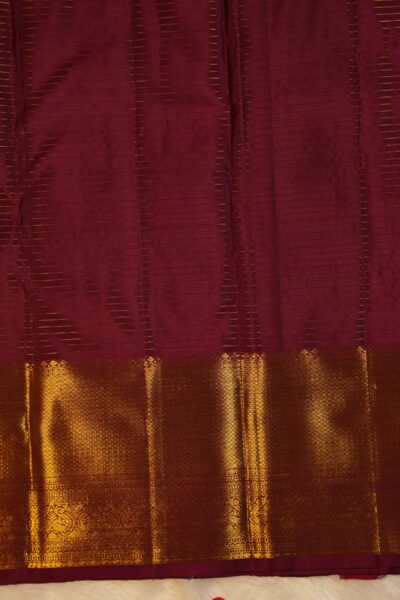 Matching maroon unstitched blouse piece featuring all-over horizontal gold zari lines and the intricate Kanchi border, perfectly complementing the handloom checked saree.
