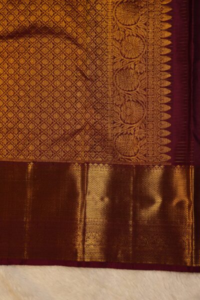 Close-up highlighting the intricate transition between the geometric diamond brocade pallu and the traditional peacock and narrative motifs on the heavy maroon border.