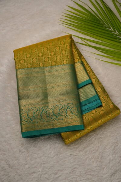 Elegantly folded outlook of the mustard yellow semi pattu art silk saree, displaying the stunning contrast between the zari checked body and the rich sea green border.