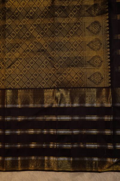 Close-up highlighting the intricate transition between the geometric diamond brocade pallu and the traditional peacock motifs on the heavy brown border.