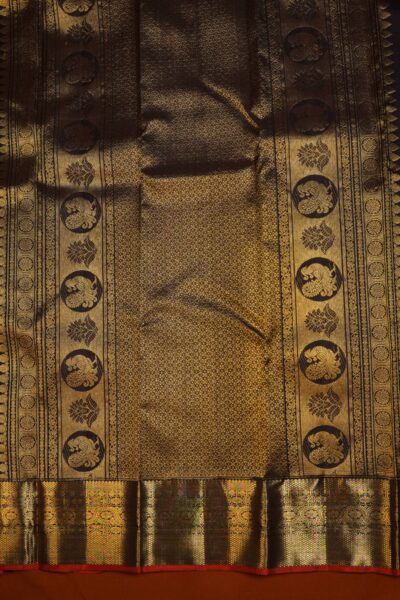 The magnificent, dense gold zari brocade pallu of the coffee brown pure handloom Kanjeevaram saree, adorned with traditional peacock and floral motifs.
